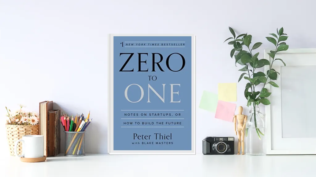 The book cover of "Zero to One: Notes on Startups, or How to Build the Future" by Peter Thiel, displayed on a white desk with various office supplies.